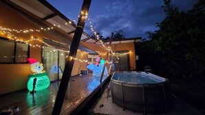 A backyard with a hot tub, string lights, and inflatable decorations.