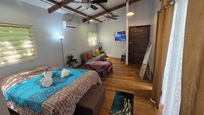 A cozy room with a bed, a small table, a sofa, and a TV.