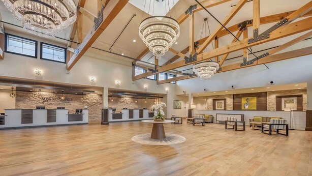 A spacious lobby with a reception desk, wooden beams, chandeliers, and a central floral arrangement. - Charming 1-bedroom apartment with fitness room, WiFi in Celebration (Celebration)