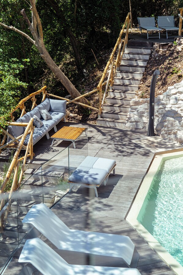 A wooden deck with a pool, lounge chairs, and a sofa with cushions. - LA FORESTALE Luxury Ecolodge (Acqualagna)