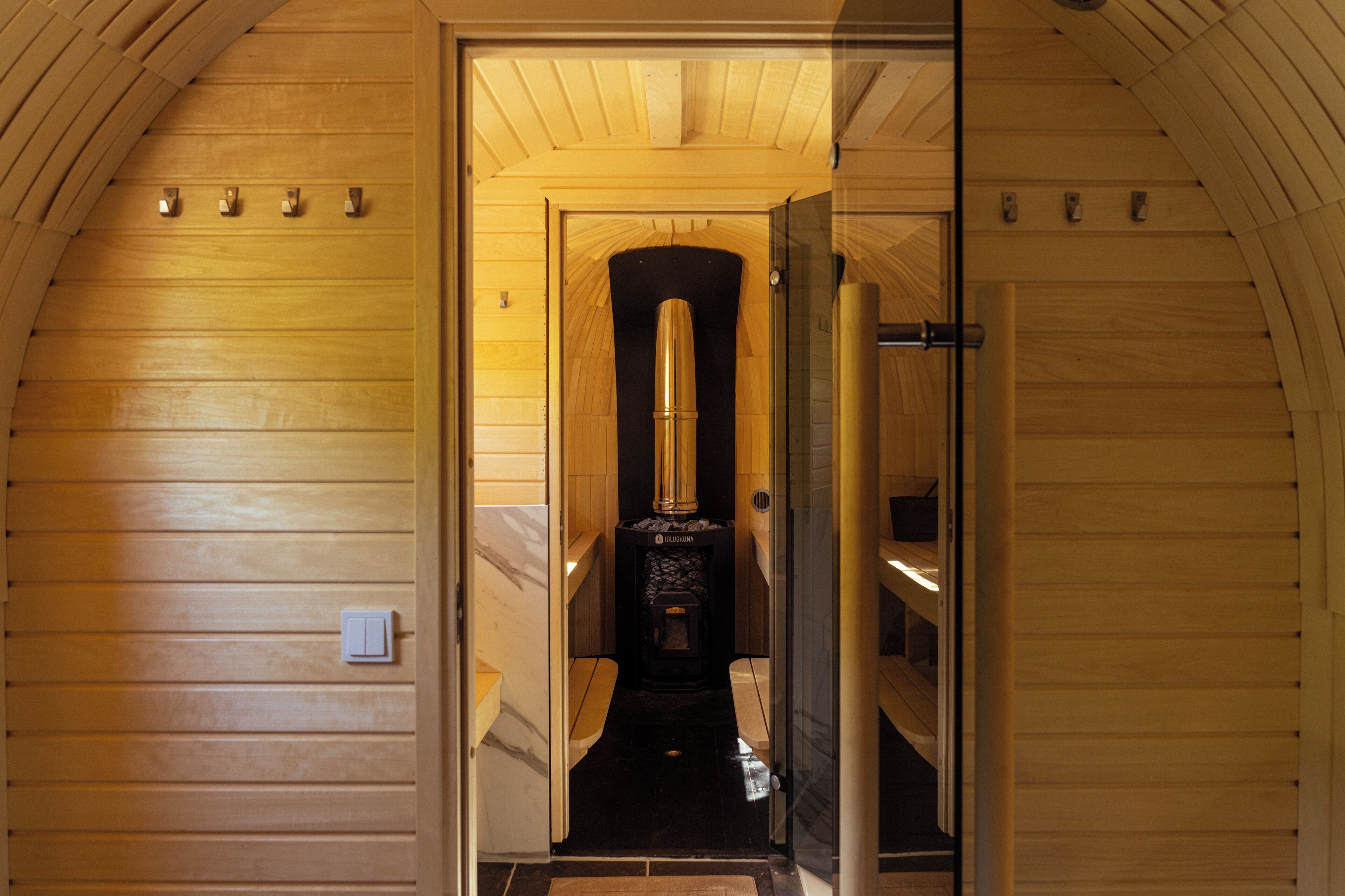 Un interno in legno con un camino nero, una porta in vetro e un soffitto in legno.