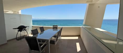 Enjoy a panoramic ocean view from this spacious balcony with a table and chairs, perfect for outdoor dining.