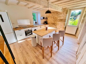 A kitchen with a wooden island, white cabinets, and a stone wall. - Nature View Cottage • Terrace • Piscina (Aguts)