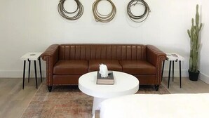 Un salon avec un canapé en cuir marron, une table basse blanche et trois éléments de décoration circulaire fixés au mur.