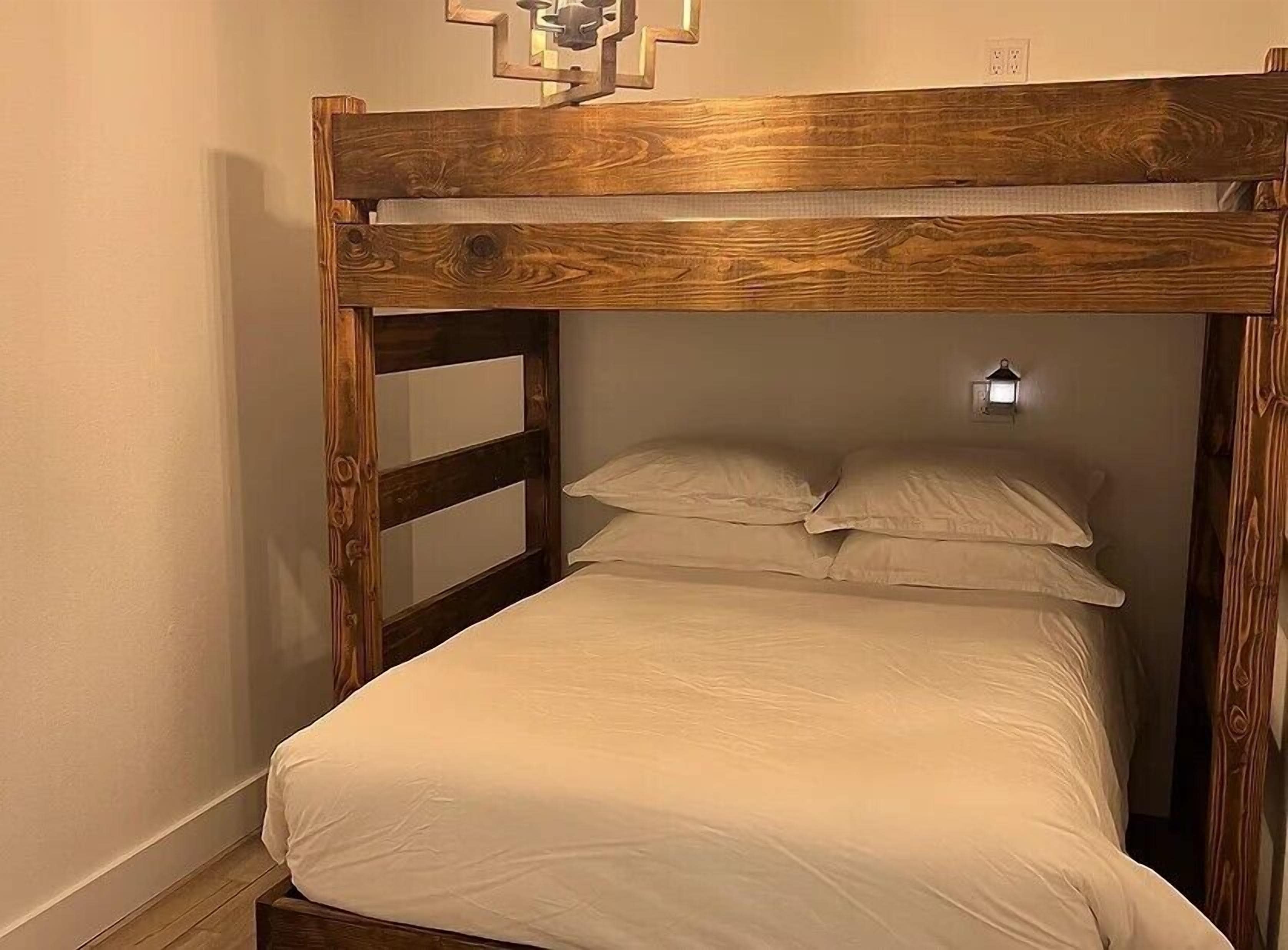 Un letto a castello con una testiera in legno e un piccolo faretto a parete sopra il letto.
