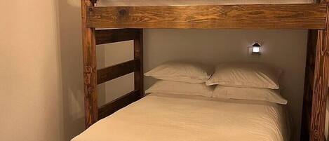 Un letto a castello con una testiera in legno e un piccolo faretto a parete sopra il letto.