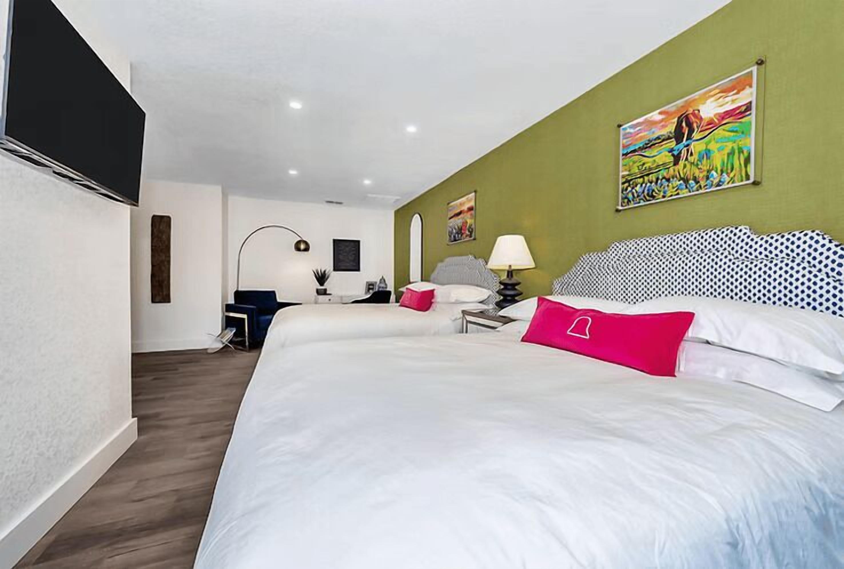 Un dormitorio moderno con una cama grande, un escritorio, una silla, una lámpara y un cuadro en la pared.