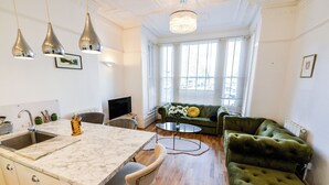Une cuisine moderne dotée d’un plan de travail et d’un évier en marbre, d’un canapé vert et d’un coin repas avec une table ronde.