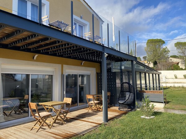 Une maison moderne dotée d’un patio couvert, de portes-fenêtres coulissantes et de mobilier d’extérieur.