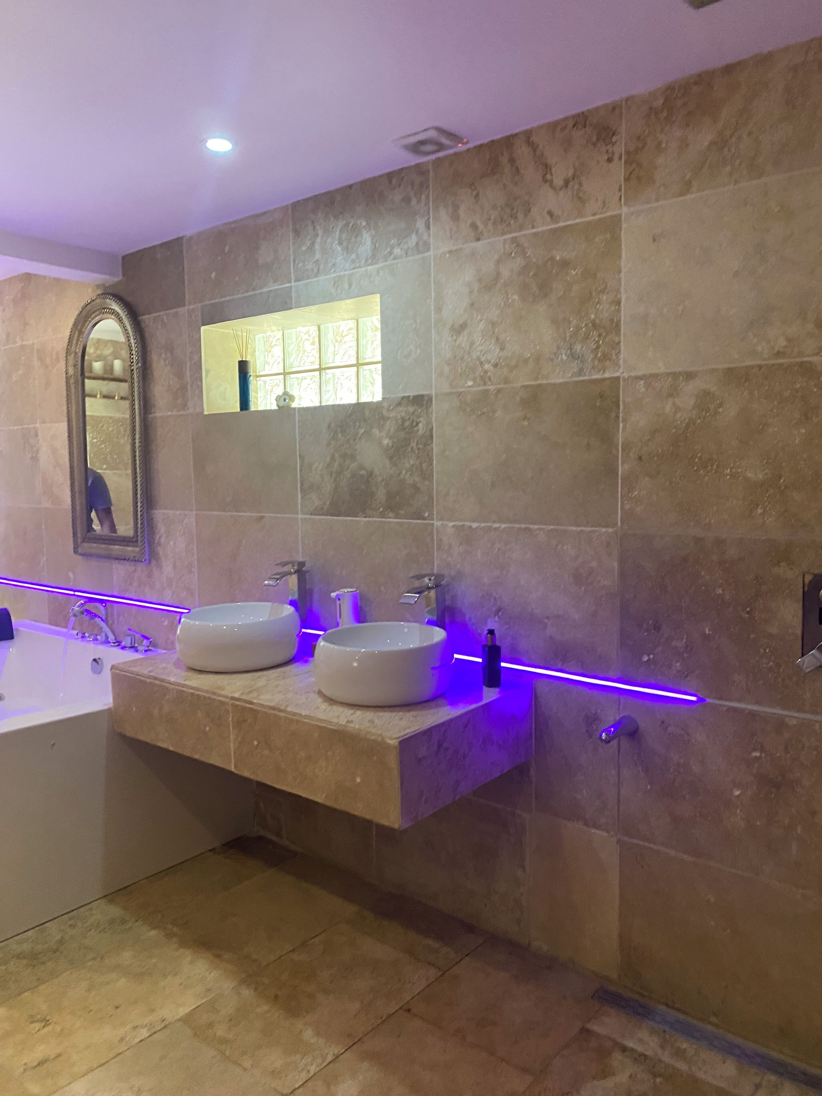 A modern bathroom with two sinks, a large mirror, and a bathtub.