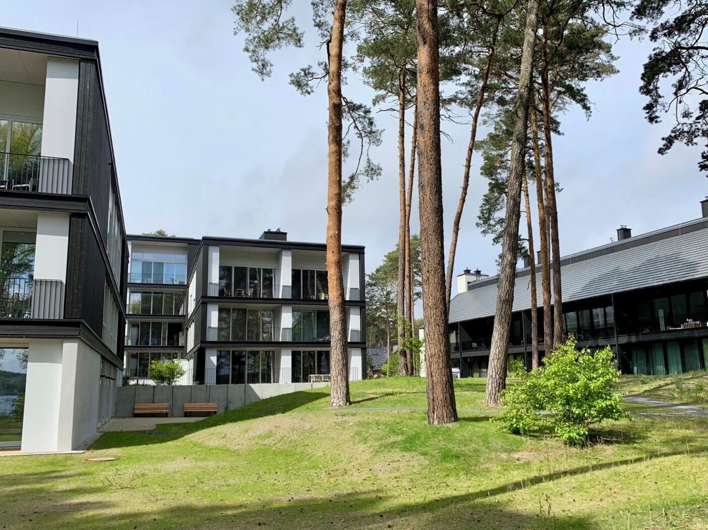 En modern byggnad med flera våningar, stora fönster och ett grönområde med träd.