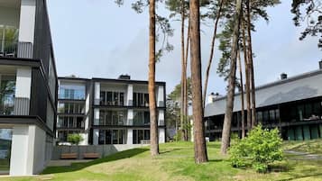 En modern byggnad med flera våningar, stora fönster och ett grönområde med träd.