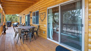 A wooden deck with a covered patio area, a dining table with chairs, and a barbecue grill. - Charming 2-bedroom Cabin with WiFi, Wood Stove and AC in serene Heber-Overgaard! (Heber-Overgaard)