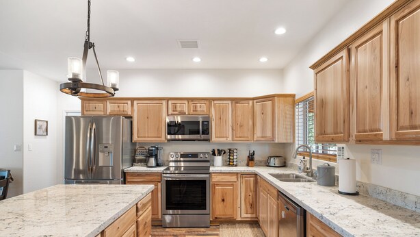 A kitchen with wooden cabinets, stainless steel appliances, granite countertops, and a central island. - Charming 2-bedroom Cabin with WiFi, Wood Stove and AC in serene Heber-Overgaard! (Heber-Overgaard)