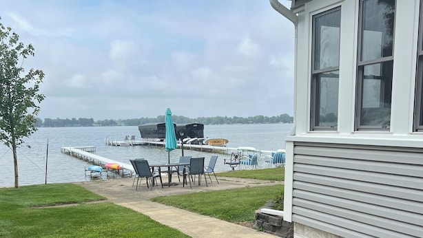 A lakeside patio with a dining table and chairs, a covered seating area, and a view of the water. - Charming Beachfront 4-bedroom cottage with WiFi, AC in Coldwater (Coldwater)