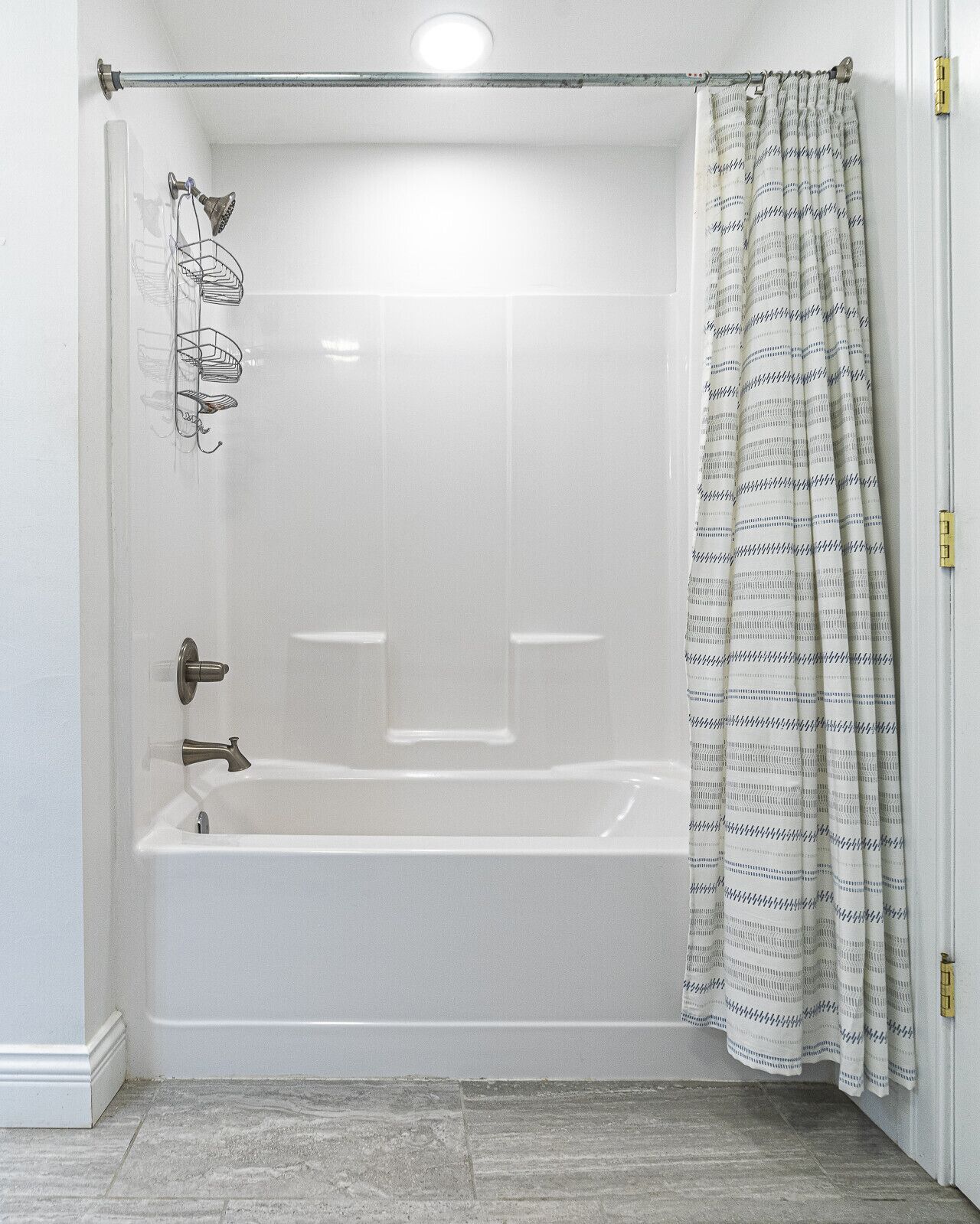 Zona de ducha con bañera, cortina de baño y un perchero para toallas.