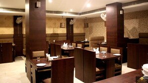 A restaurant with booths and tables, each set with plates, cutlery, and glasses. - HOTEL GK PALACE (East Jorhat)