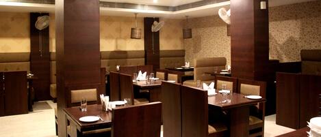 A restaurant with booth seating, high tables, and a patterned wall.