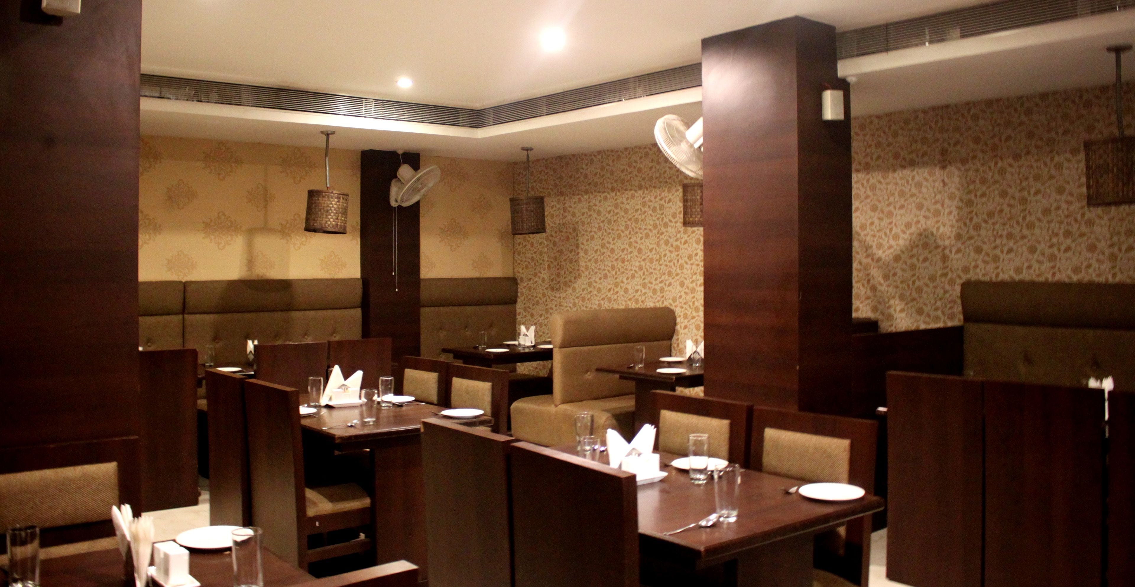 Un restaurant avec des banquettes et des tables, chacune étant dressée avec des assiettes, des verres et des couverts.