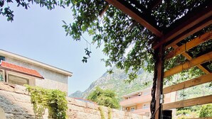 Eine Außenpatio mit Steinboden, Metallklappstühlen und einer Holz-Pergola.