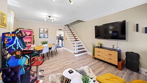 Ein modernes Wohnzimmer mit Flachbildfernseher, einer Treppe und einem Essbereich.