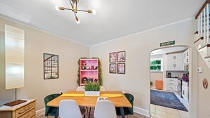 Ein Essbereich mit einem Holztisch, vier Stühlen, einer Topfpflanze und einem an der Wand befestigten Regal mit Dekoration.