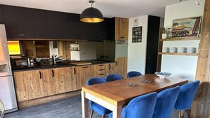 Eine moderne Küche mit dunklen Schränken, einem Holztisch und blauen Stühlen.