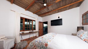 A bedroom with a large bed, a desk, a chair, and a TV.