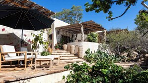 A patio with outdoor furniture, a pergola, and a stone staircase leading to a covered area.