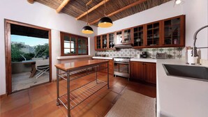 A kitchen with wooden cabinets, a stove, and a hanging light fixture.