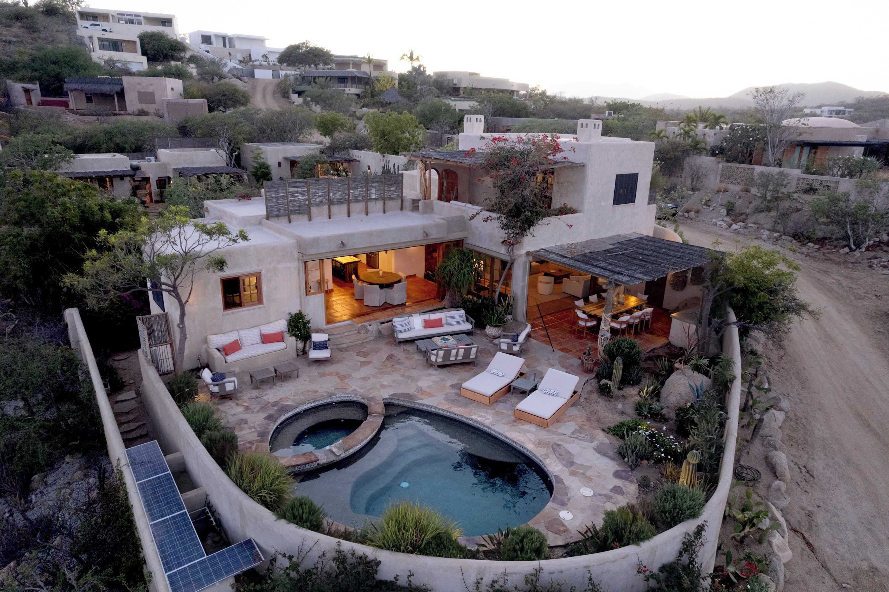 Une maison moderne dotée d’une piscine, d’un espace salon extérieur et d’un jardin.