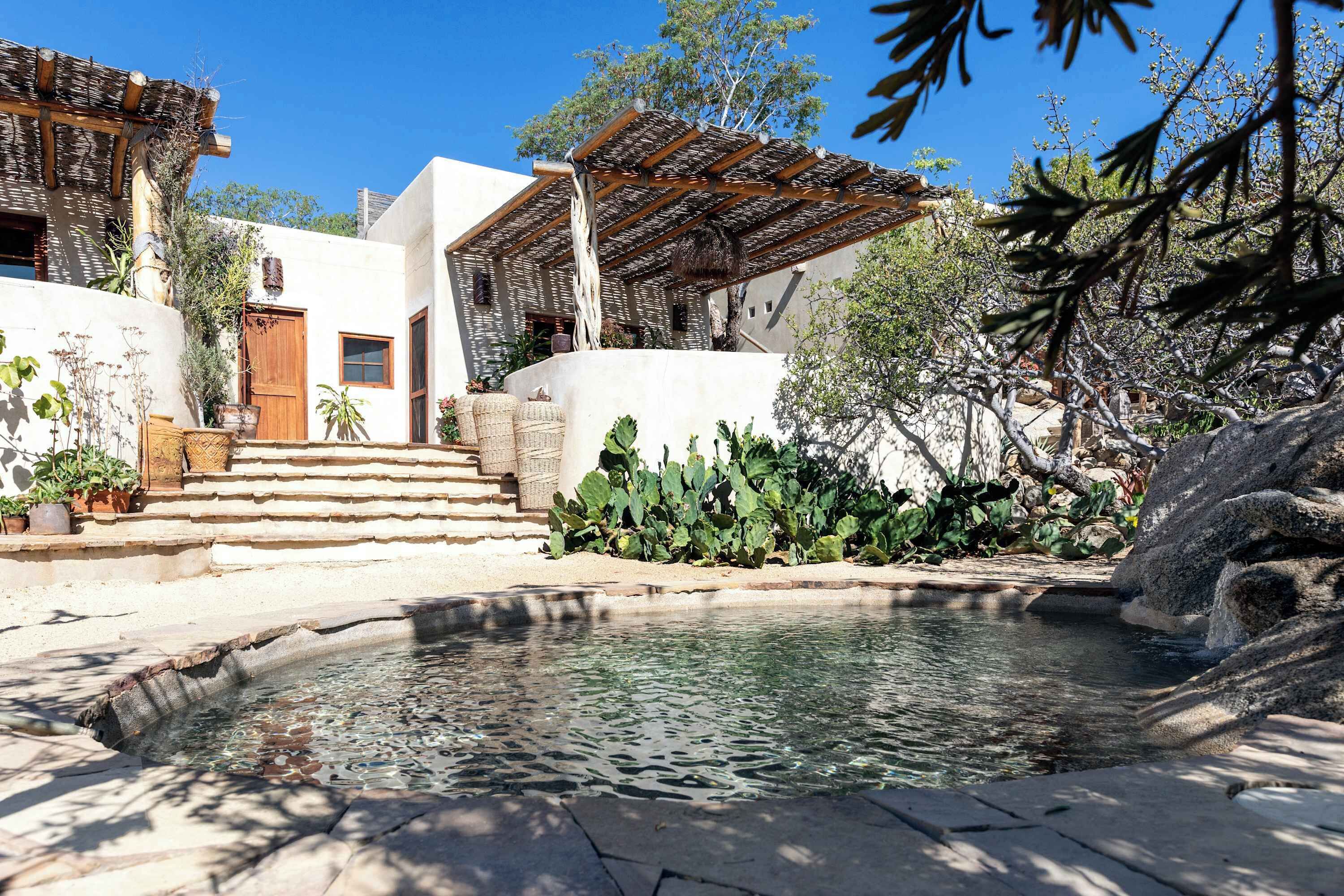 Ein Innenhof mit Pool, Treppen zu einer Holztür und einer Pergola.