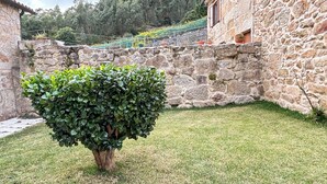 Edifici de pedra amb un petit jardí i un arbust ben tallat.