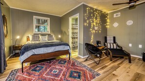A bedroom with a bed, a desk, a chair, a patterned rug, and string lights on the wall. - Pet-Friendly Creekside Cabin w/ Hot Tub 2BR/2 Bath (Ellijay)