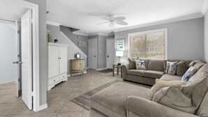 A living room with a beige sofa set, a white cabinet, and a ceiling fan.