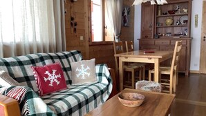 A cozy cabin interior with a wooden sofa, a dining table, and a wooden cabinet.