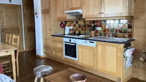 A kitchen with wooden cabinets, a stove, an oven, and a tiled backsplash.