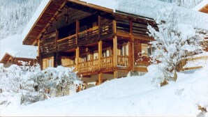 A wooden chalet with a balcony, surrounded by snow-covered trees. - Ground floor, terrace, parking, tv, ski locker, 39m², Le Grand Bornand (Le Grand-Bornand)