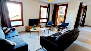 A modern living room with a sofa, armchairs, a coffee table, and a TV. - 50m from ski slopes, balcony, tv, 115m², Montalbert (La Plagne)