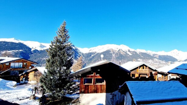 A snow-covered mountain village with wooden cabins and a large evergreen tree. - 50m from ski slopes, balcony, tv, 115m², Montalbert (La Plagne)