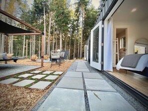 Une terrasse extérieure moderne, avec un chemin de pierre menant à un espace détente agrémenté de chaises et d’une table.