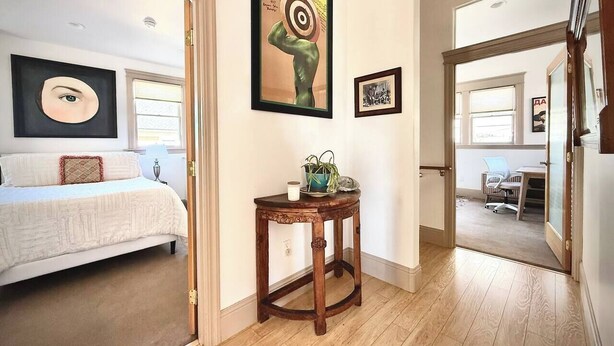 A bedroom with a bed, a small wooden table with a plant, and artwork on the wall. - Spacious Downtown Spot-Sleeps 8! (Arcata)