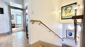 A staircase with a wooden handrail and a picture frame on the wall. - Spacious Downtown Spot-Sleeps 8! (Arcata)