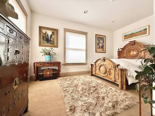 A bedroom with a wooden bed, a dresser, a rug, and framed artwork on the walls.