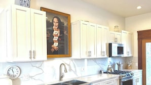 A kitchen with white cabinets, a marble countertop, a stove, a sink, and a clock. - Spacious Downtown Spot-Sleeps 8! (Arcata)
