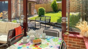 Ein Wintergarten mit einem für Tee gedeckten Tisch, Stühlen und einer Couch.