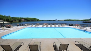 A swimming pool with lounge chairs and a view of a lake. - Waterfront 2BR/2BA Condo, Walk-Out Deck to Lake, Pools & Hot Tub (Village of Four Seasons)