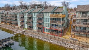 A multi-story hotel with balconies, a dock, and a river. - Waterfront 2BR/2BA Condo, Walk-Out Deck to Lake, Pools & Hot Tub (Village of Four Seasons)