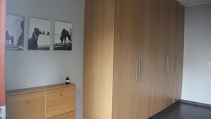 Una habitación con un armario de madera, un tocador de madera y tres cuadros en la pared.