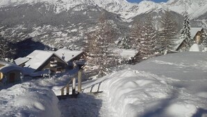 Un paysage de montagne enneigé, avec un bâtiment de style chalet au premier plan.